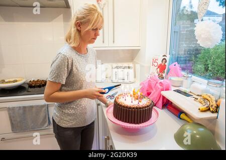 A mother holds out a birthday cake for a little girl on her 7th birthday Stock Photo