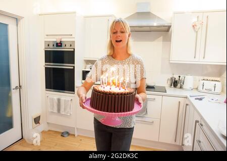 A mother holds out a birthday cake for a little girl on her 7th birthday Stock Photo