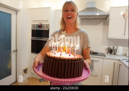 A mother holds out a birthday cake for a little girl on her 7th birthday Stock Photo