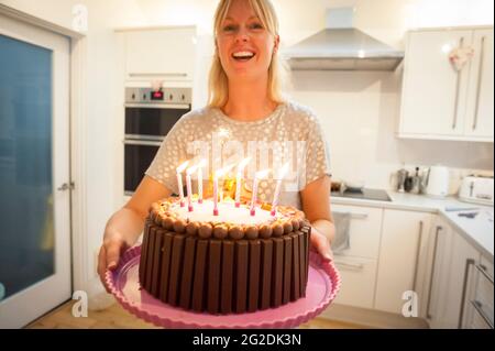 A mother holds out a birthday cake for a little girl on her 7th birthday Stock Photo