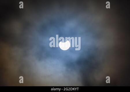 Partial solar eclipse shot around 11am on 10.06.2021 amongst cloud cover in West Sussex, England. Stock Photo