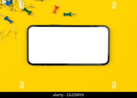 School supplies mobile phone mockup, offie table with colored pins, school stationery template concept Stock Photo