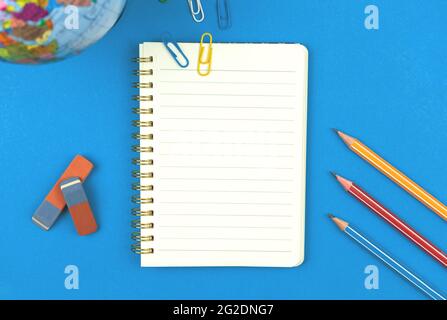 Blank lined notebook mockup with school stationery, pencils on blue background, flat lay composition top view photo Stock Photo