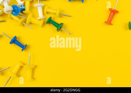 Yellow office desktop with a lot of colored push pins, border of school supplies stationery, norder composition with copy space Stock Photo