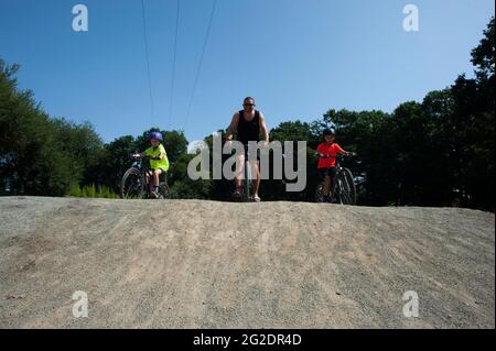 A family riding bikes in France in the summer on cycle paths exploring nature. Stock Photo