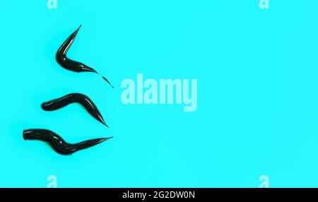 Three thick black cream smears (charcoal toothpaste) on light blue background, view from above, space for text right side Stock Photo