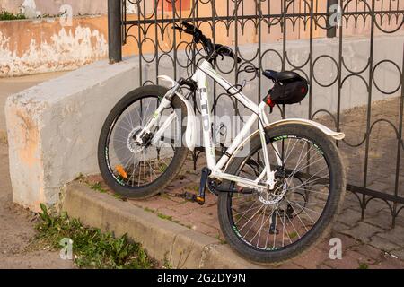 BELARUS, NOVOPOLOSK - 09 JUNE, 2021: White bike pinned to the fence close up Stock Photo