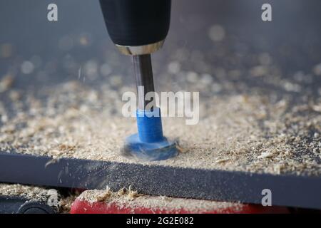 Drilling through holes in chipboard with a tool Stock Photo