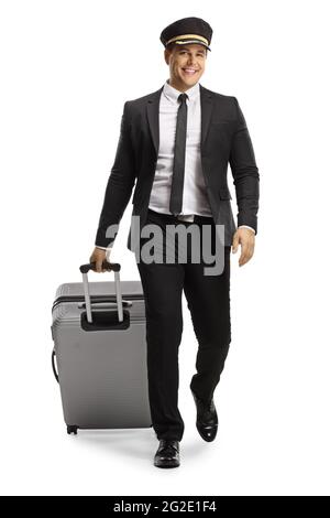 Full length portrait of a pilot in a uniform walking towards camera and pulling a suitcase isolated on white background Stock Photo