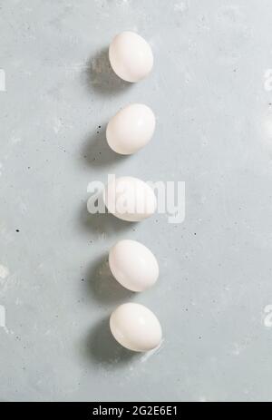 Five white chicken eggs lie on a gray background. Healthy nutrition concept. Top view. Stock Photo