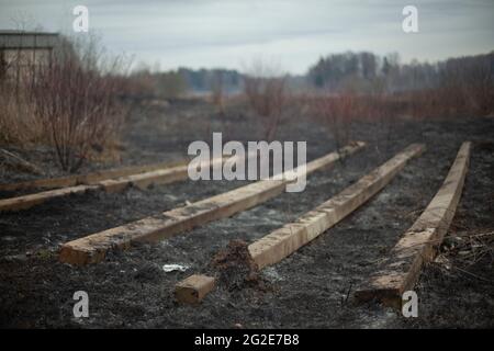 Concrete beams on the ground. Build materials after a fire. Remains on the scorched earth. Concrete blocks. Stock Photo