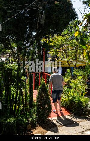 An old man walking towards a narrow bridge between the gardens of Higino da Silveira square in a sunny day, Alto district. Stock Photo