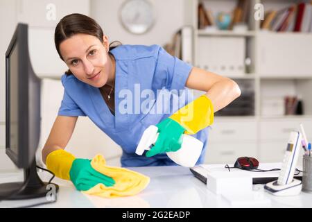 Portrait of a young woman cleaning an office desk Stock Photo
