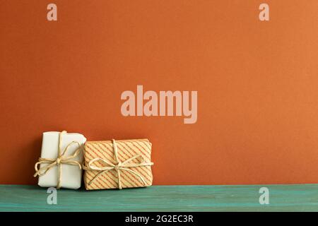 White and stripe pattern gift boxes on green wooden table. red wall background Stock Photo