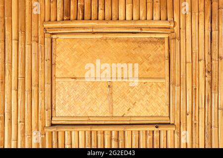 Woven window panel on bamboo wall Stock Photo