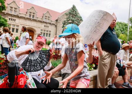 Bloomington, US. 10th June 2021. A girl catches a Brood X cicada during the demonstration.Anti-vaxxers and anti-maskers gathered at Indiana University's Sample Gates to protest against mandatory Covid vaccinations IU is requiring for students, staff and faculty during the upcoming fall semester. The protesters say their constitutional rights are being infringed, and have launched a law suit. Credit: SOPA Images Limited/Alamy Live News Stock Photo