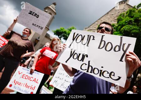 Bloomington, US. 10th June 2021. Protesters holding placards gather at Indiana University's Sample Gates during the demonstration.Anti-vaxxers and anti-maskers gathered at Indiana University's Sample Gates to protest against mandatory Covid vaccinations IU is requiring for students, staff and faculty during the upcoming fall semester. The protesters say their constitutional rights are being infringed, and have launched a law suit. Credit: SOPA Images Limited/Alamy Live News Stock Photo