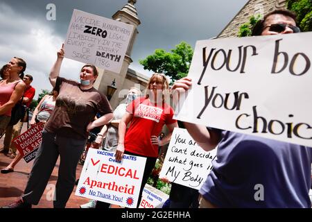 Bloomington, US. 10th June 2021. Protesters holding placards gather at Indiana University's Sample Gates during the demonstration.Anti-vaxxers and anti-maskers gathered at Indiana University's Sample Gates to protest against mandatory Covid vaccinations IU is requiring for students, staff and faculty during the upcoming fall semester. The protesters say their constitutional rights are being infringed, and have launched a law suit. Credit: SOPA Images Limited/Alamy Live News Stock Photo