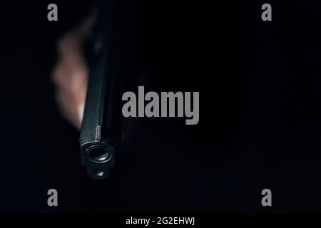 Close-up of black gun in hand. Dangerous pistol in hand. Firearms in shadows. Crime or defense. Copy space. Stock Photo