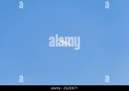 white passenger plane with tourists flying in the blue sky Stock Photo