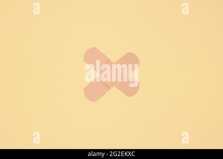 two strips of adhesive plaster tape on skin colored paper background Stock Photo