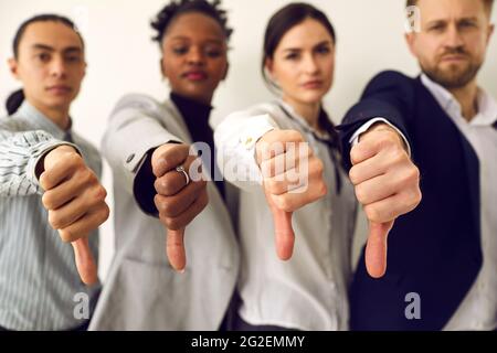 Group of diverse business people giving thumbs down showing dislike of bad work results Stock Photo