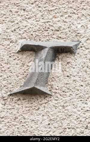 Capital letter T on roughly plastered wall Stock Photo