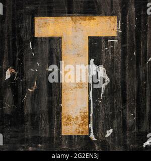 Weathered golden letter T on black background Stock Photo