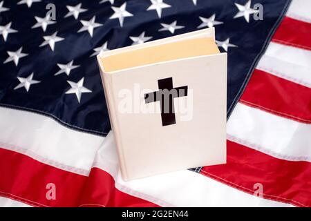 Holy Bible book with a cross on American flag. Stock Photo