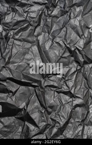 Black color background from sheet of crumpled carton, vertical view of abstract texture wrinkled cardboard material, pattern background. Stock Photo