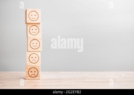 emotion face symbol on wooden blocks. Service rating, ranking, customer review, satisfaction, evaluation and feedback concept Stock Photo