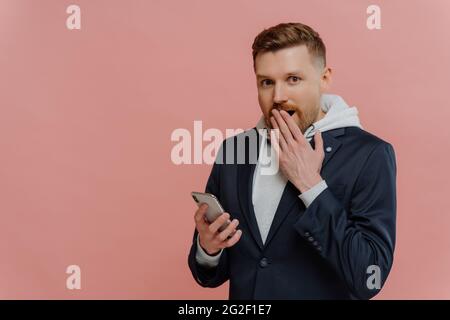 Young man receiving shocking message on smartphone Stock Photo