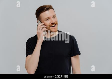 Excited man having pleasant conversation on mobile phone and feeling happy Stock Photo