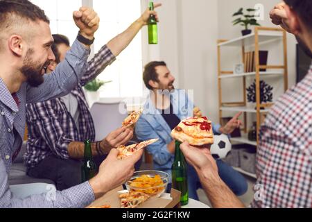 Happy young people watch a football game on TV Stock Photo