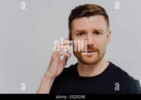Worried man having unpleasant conversation on mobile phone and feeling unhappy Stock Photo