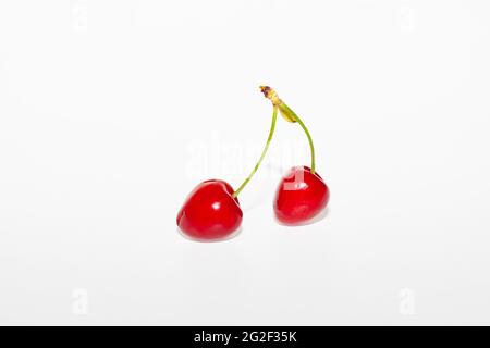 Two cherries joined by the stem isolated in the center on a white background. Stock Photo