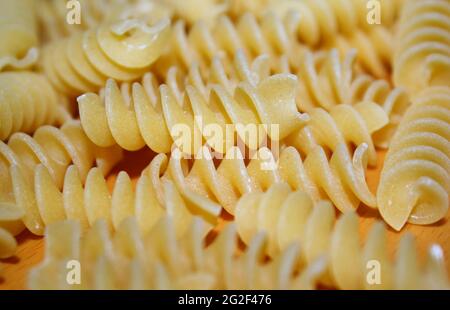 Uncooked Fusilli Italian pasta isolated on wood background. Stock Photo