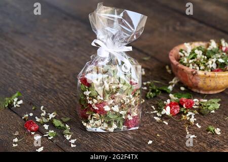 Homemade tea mix made from cherry blossoms, young leaves and dried fruit, in a cellophane bag on a table Stock Photo