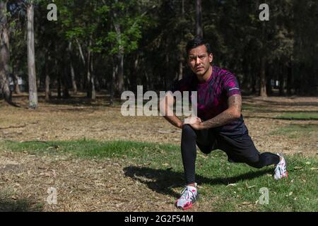 Latin man exercising in the morning, performing leg stretches, splints. Stock Photo