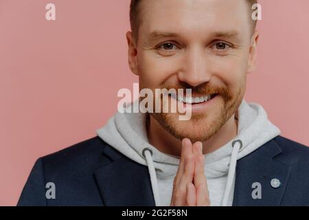 Happy man making praying gesture and smiling at camera Stock Photo