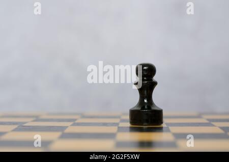Wooden black pawn on a chessboard. Chess pieces, side view Stock Photo