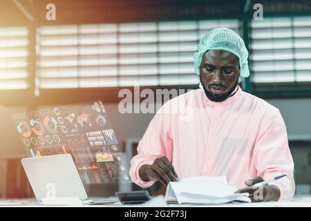 Factory worker working with advanced technology computer device with hologram mornitor display show AI business report data information support workin Stock Photo