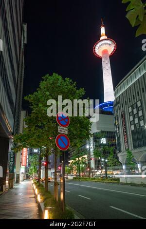 Tokyo, Japan - 15.05.2019: Vertical low angle shot of Kyoto Tower illuminated in different colors in the night from the street below Stock Photo