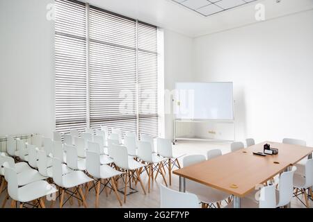 Meeting room with a large white school board and white chairs in modern office. Stock Photo