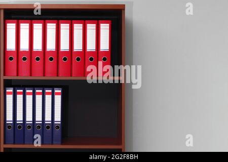 red and blue office ring binder folders on shelves with copy space Stock Photo
