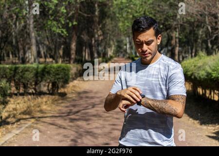 Running man looking sport watch. Male runner jogging using smart-watch outside Stock Photo
