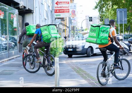 Delivery men with backpack on bicycle in the street. Courier delivering food during coronavirus pandemic. Milan, Italy - June 16, 2020 Stock Photo