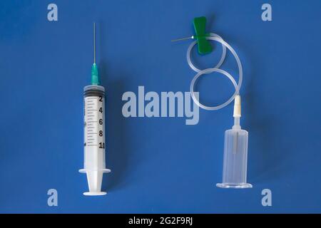 Comparison between classic syringe and modern vacutainer with butterfly needle. Isolated on blue background Stock Photo