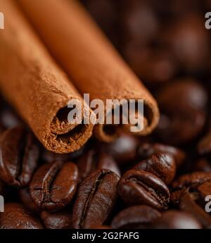 Macro shot of cinnamon sticks lying on coffee beans background. Stock Photo