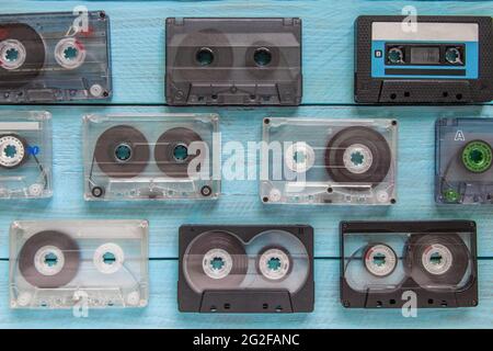 Many audio cassettes lie in a checkerboard pattern on a blue wooden background Stock Photo